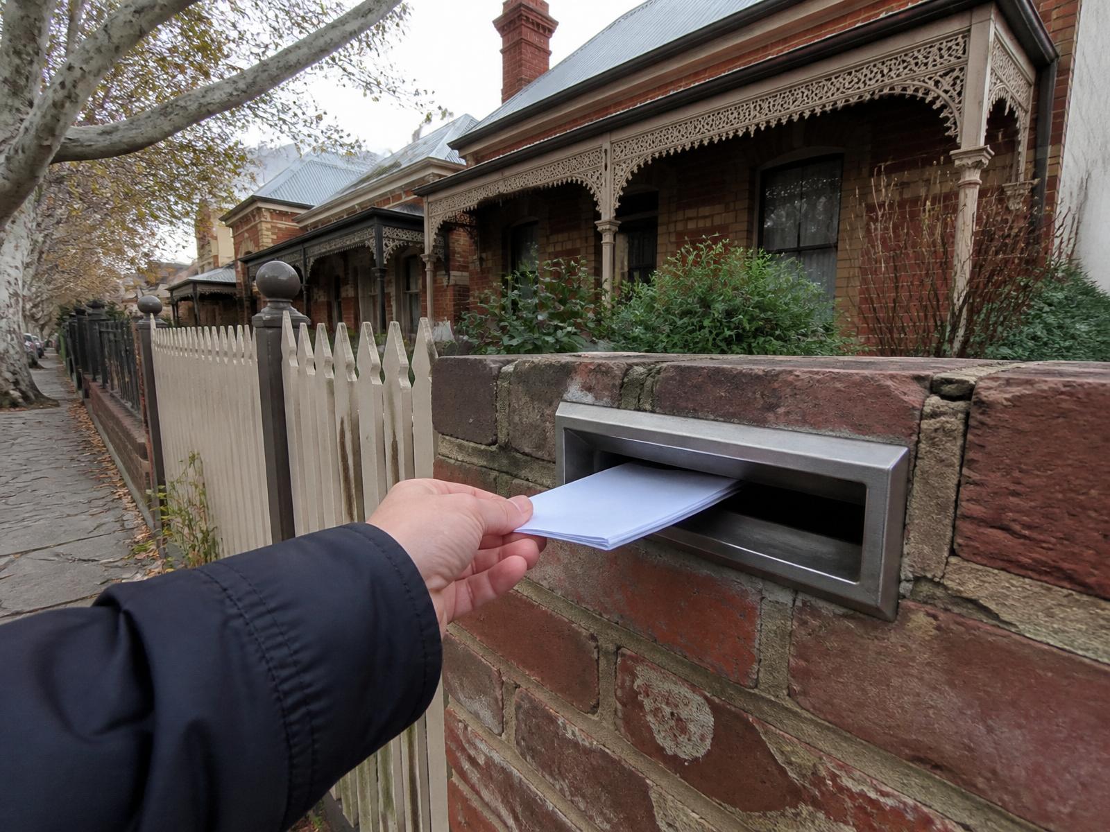 Flyer being placed into a letterbox on a Fitzroy terrace house